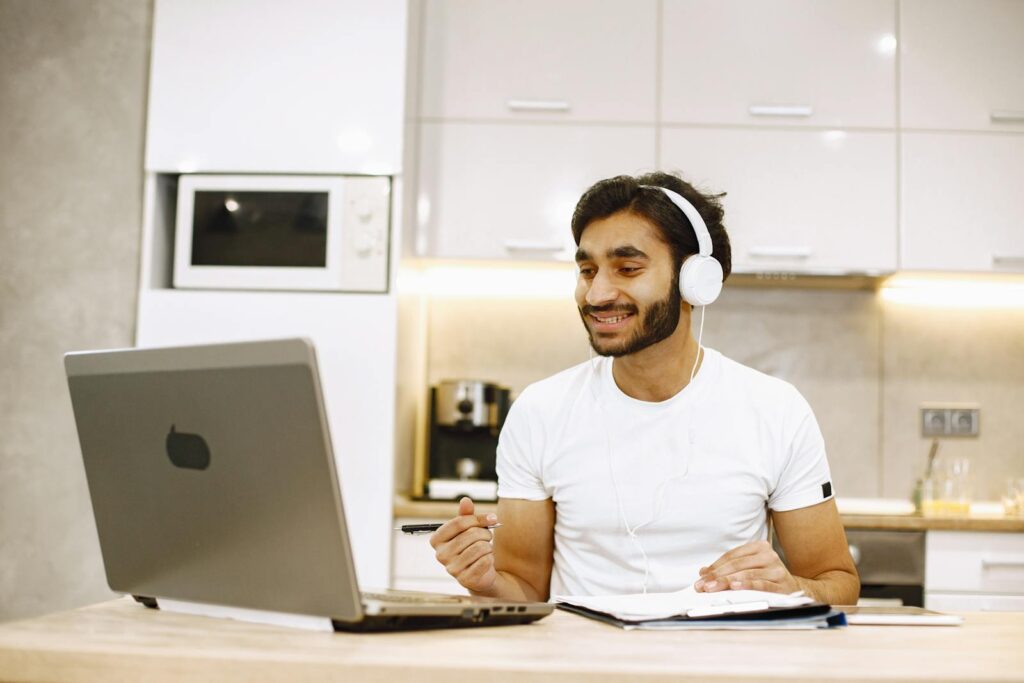 Smiling Man in Headphones Talking on Call on Laptop
